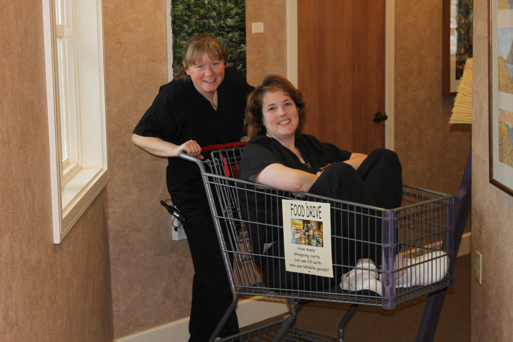Kathryn pushing Janet in a shopping cart for a food drive for the local Food Pantry
