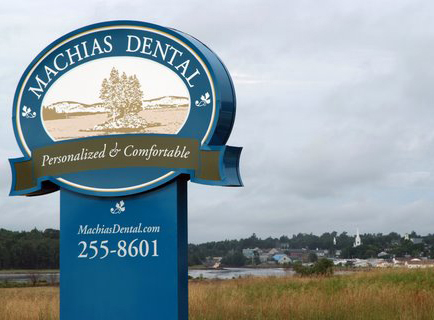Machias Dental signage with field, river, and town in the background